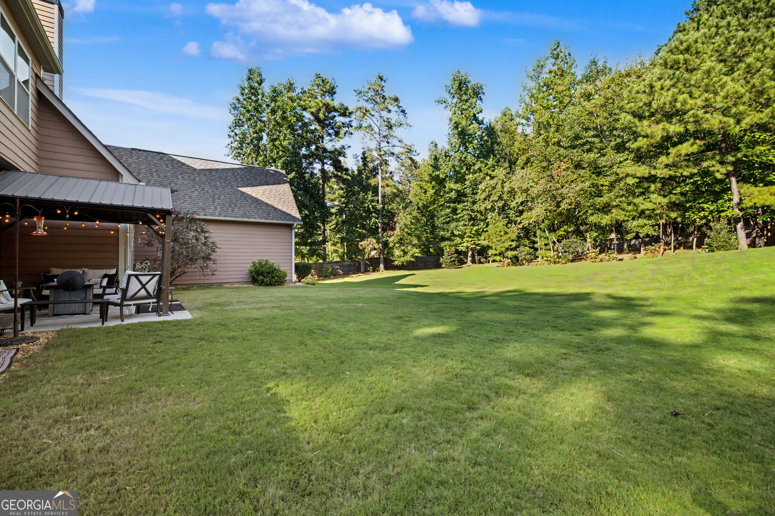 Home backyard with a spacious lawn and covered patio with outdoor seating.