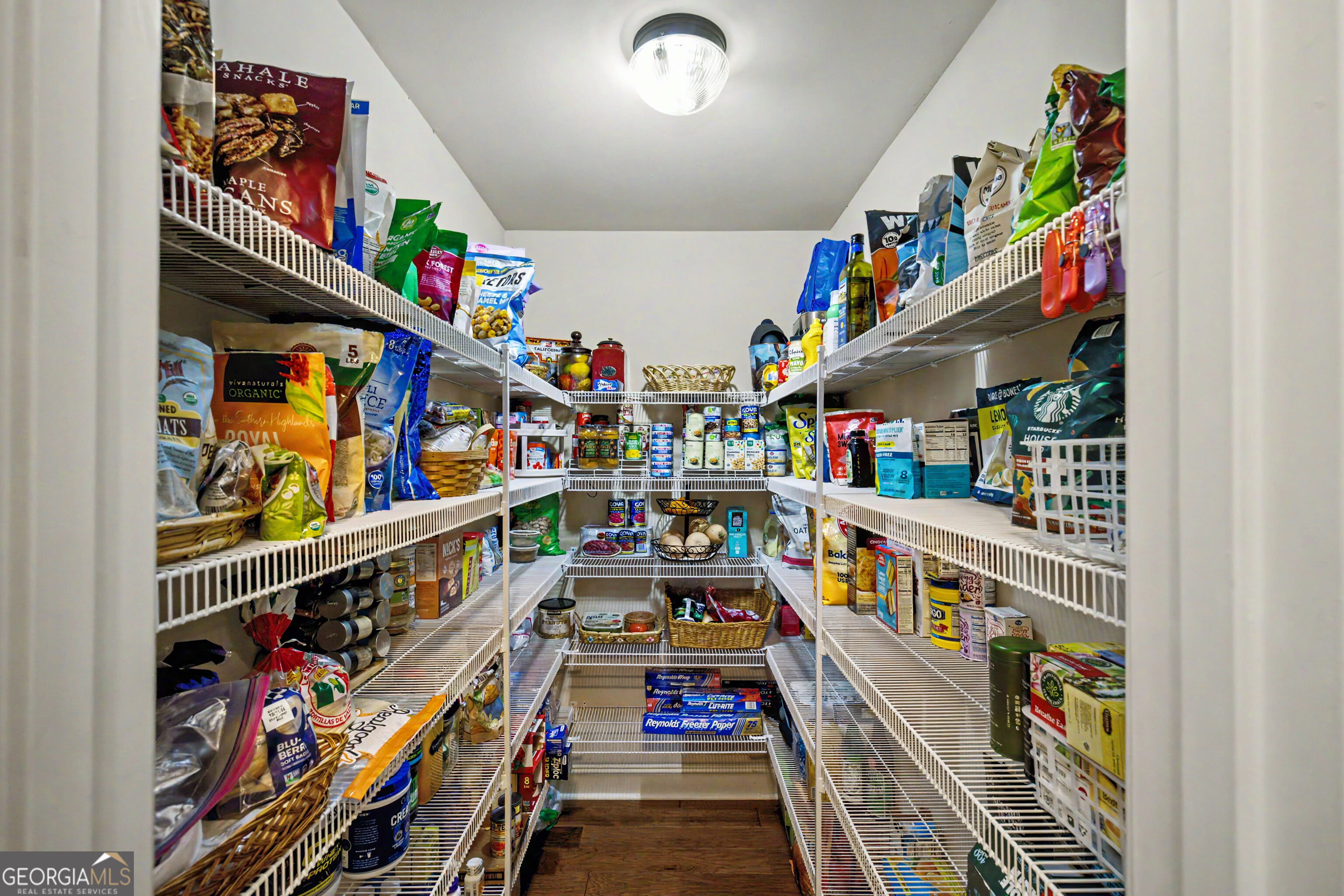 Walk-in pantry with white wire shelving stocked with food and household supplies.