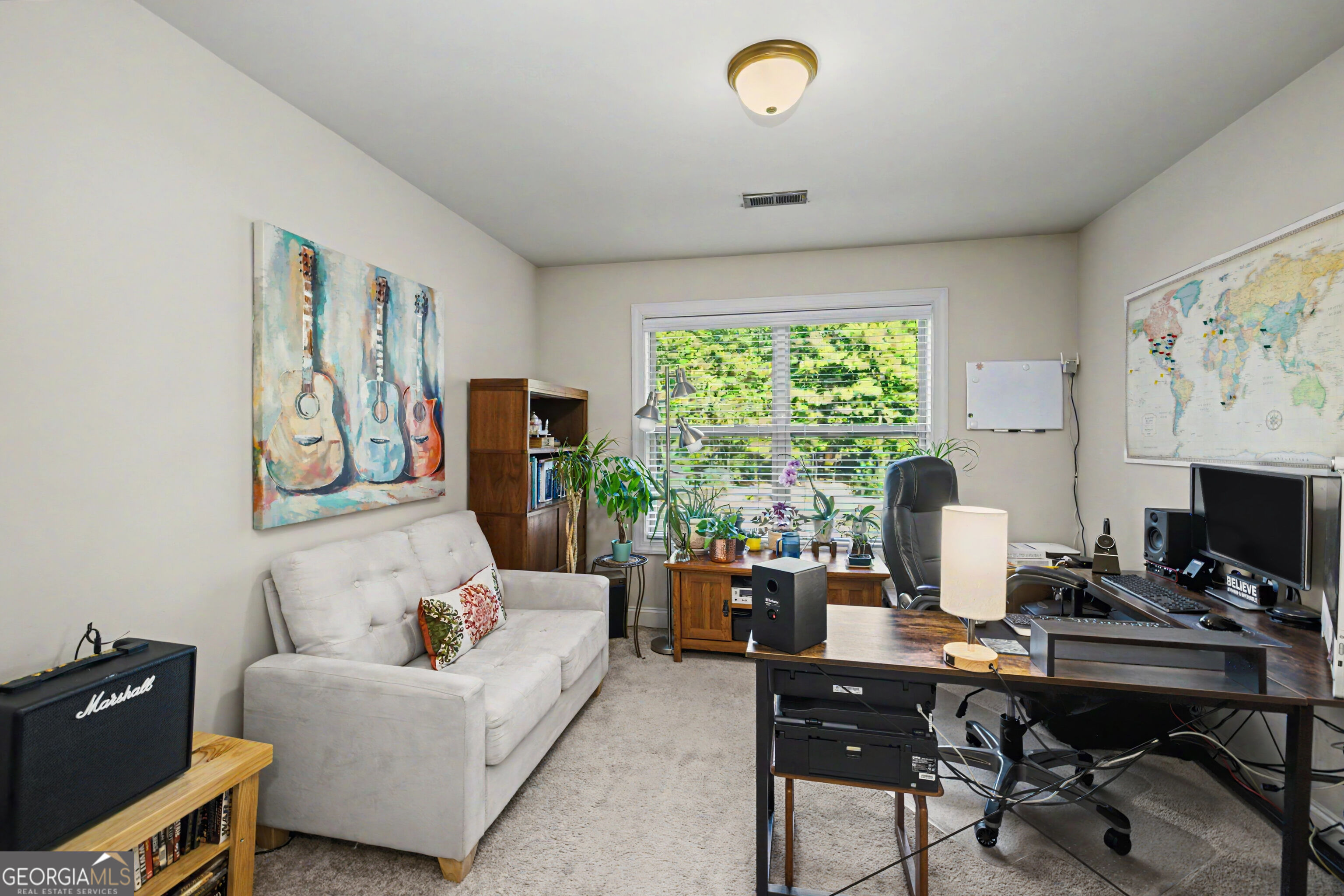 Home office with a computer workstation, window-side plants, and a light sofa.