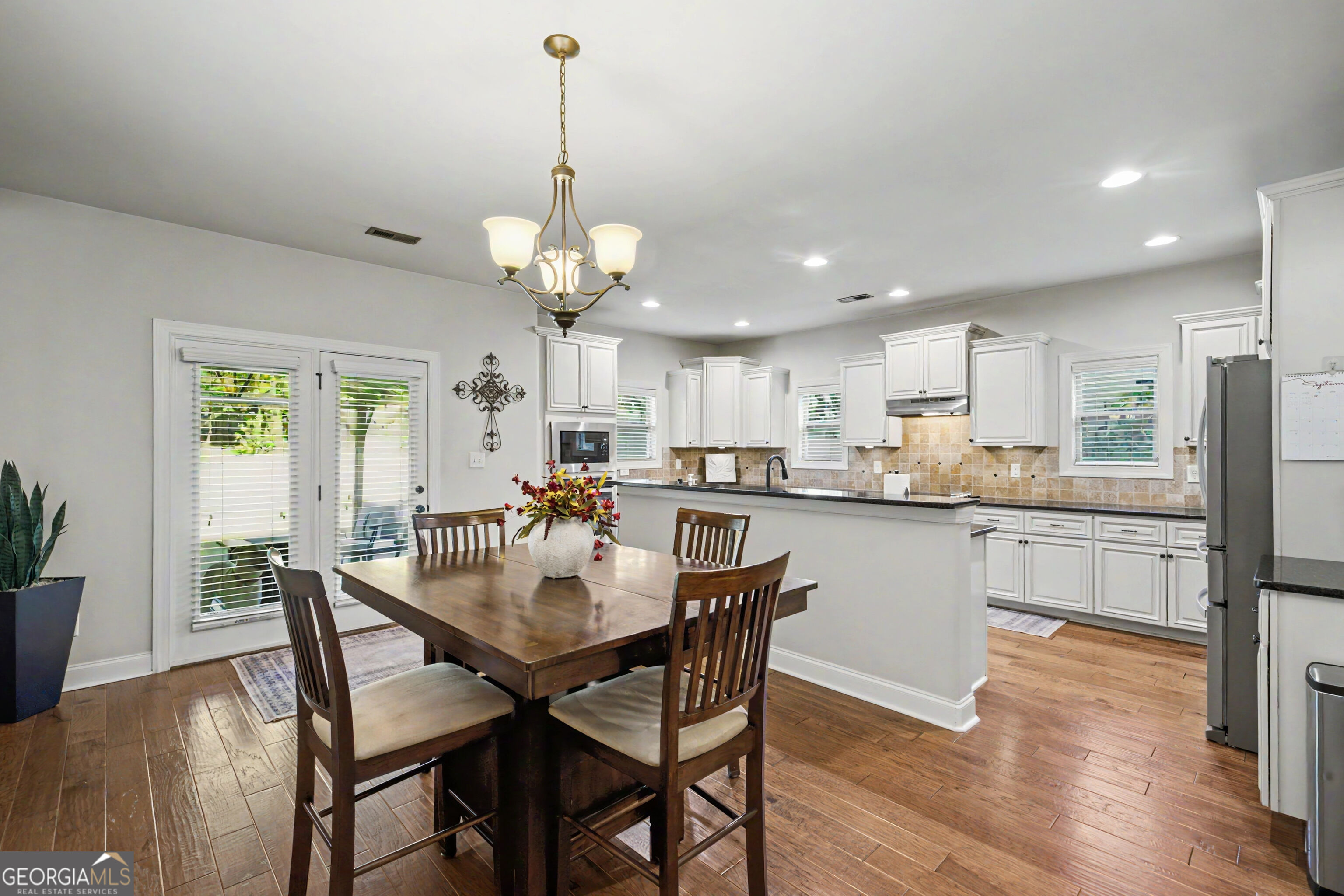 Kitchen and dining area with white cabinets, a peninsula island, and a dark wood dining table.