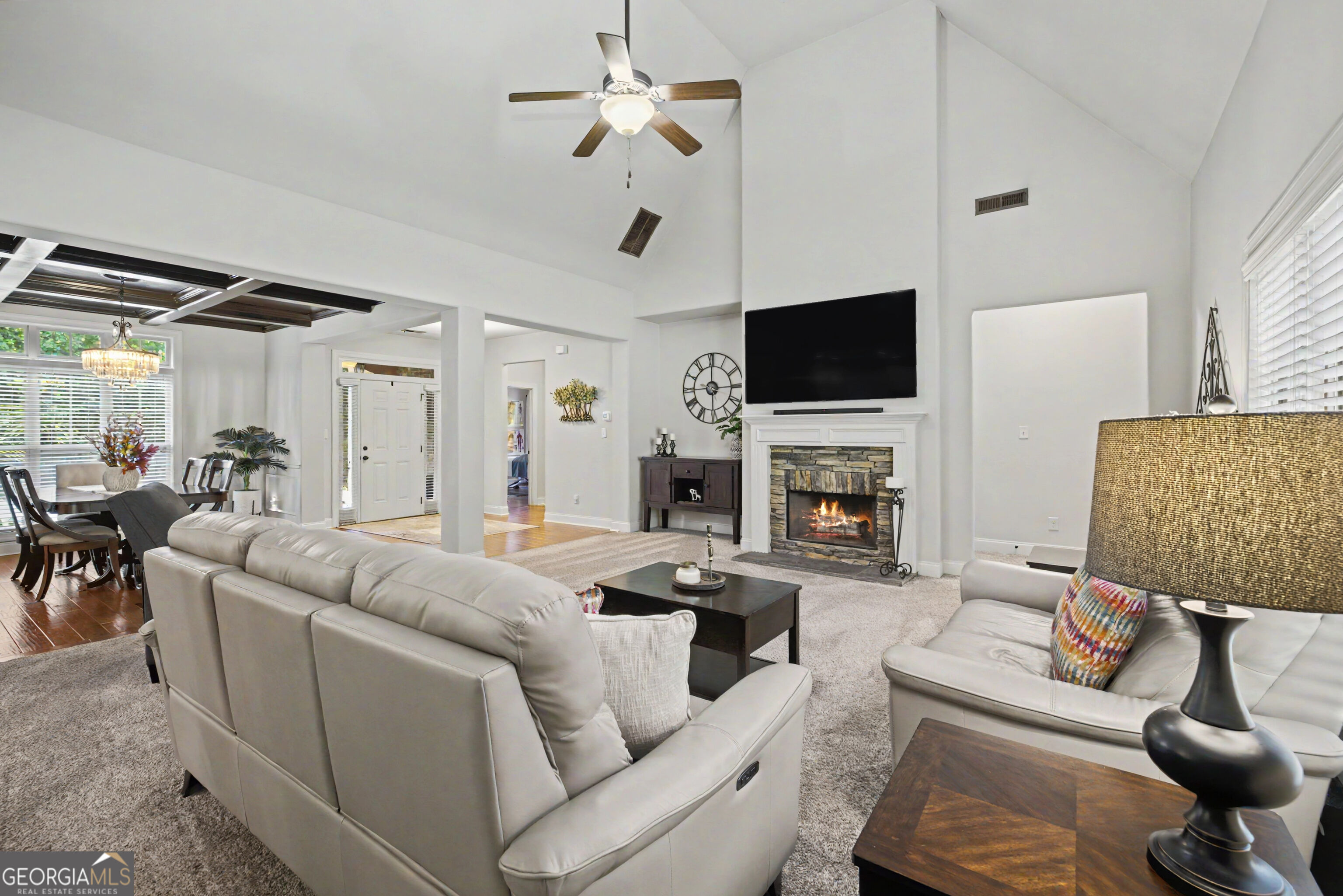 Living room with vaulted ceiling, stone fireplace, and open dining area.