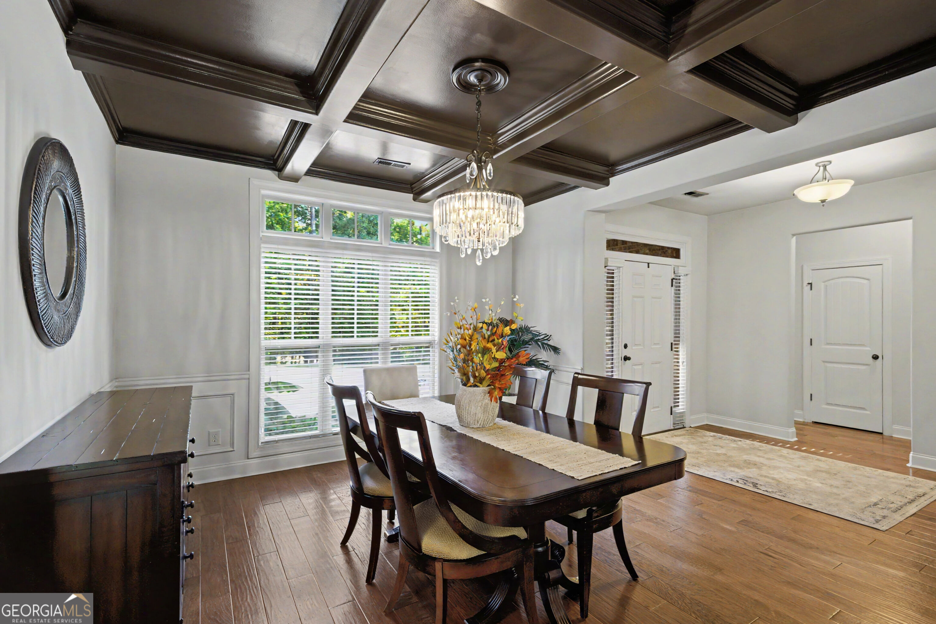 Dining room with a dark coffered ceiling, crystal chandelier, and dark wood dining set.