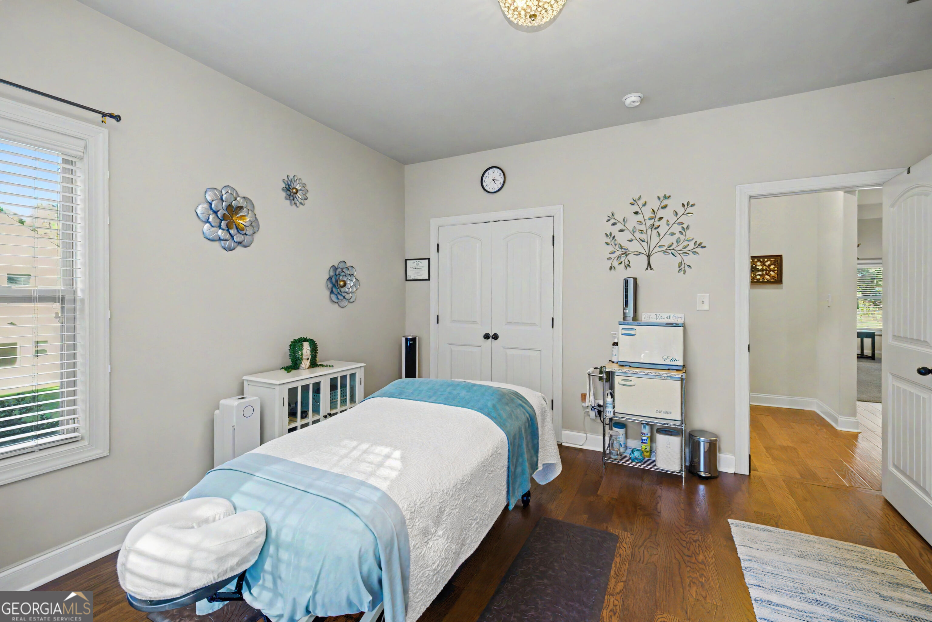 Massage treatment room with a padded table, spa equipment, and dark hardwood floors.
