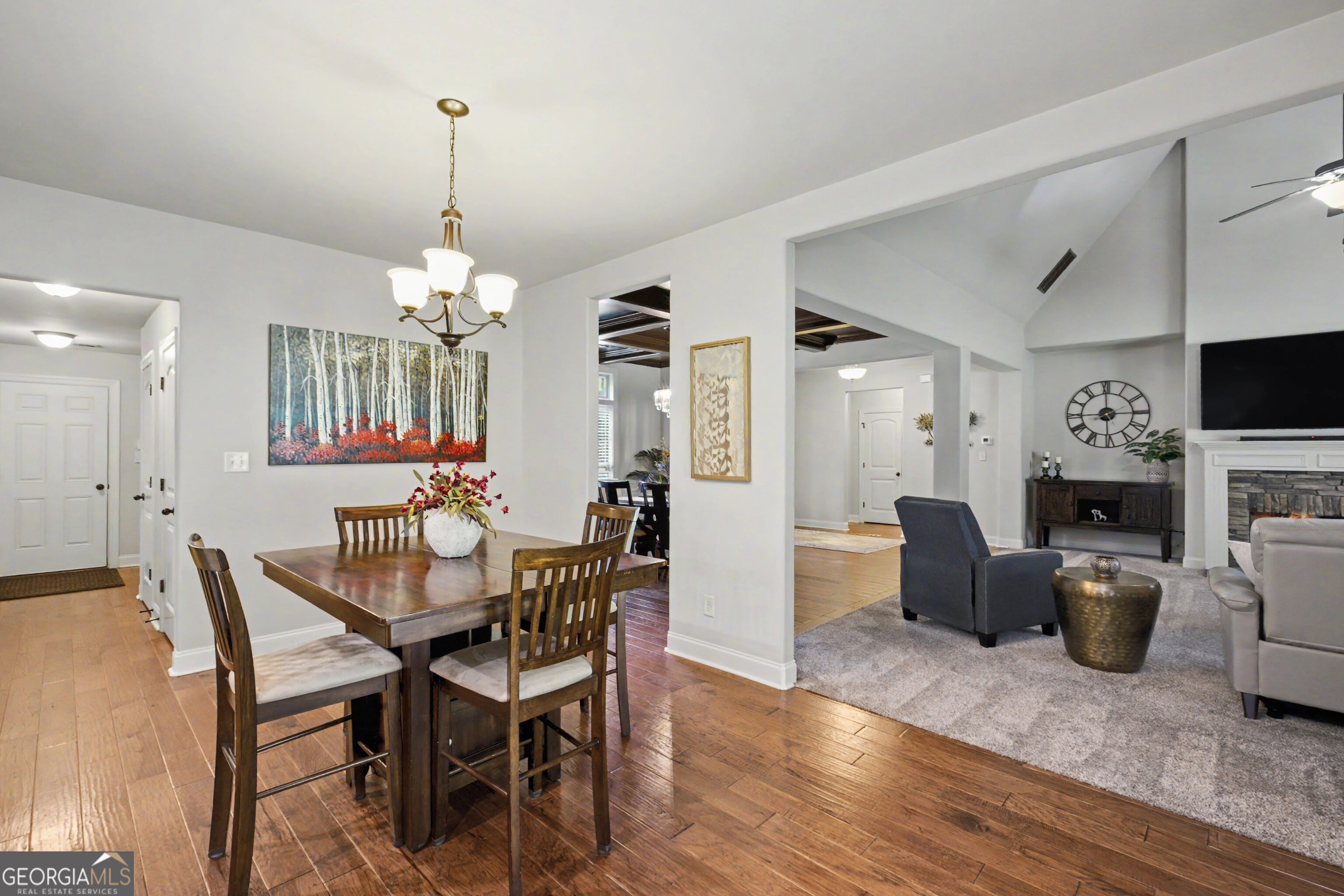 Dining area opening into a living room with a fireplace, television, and hardwood floors.