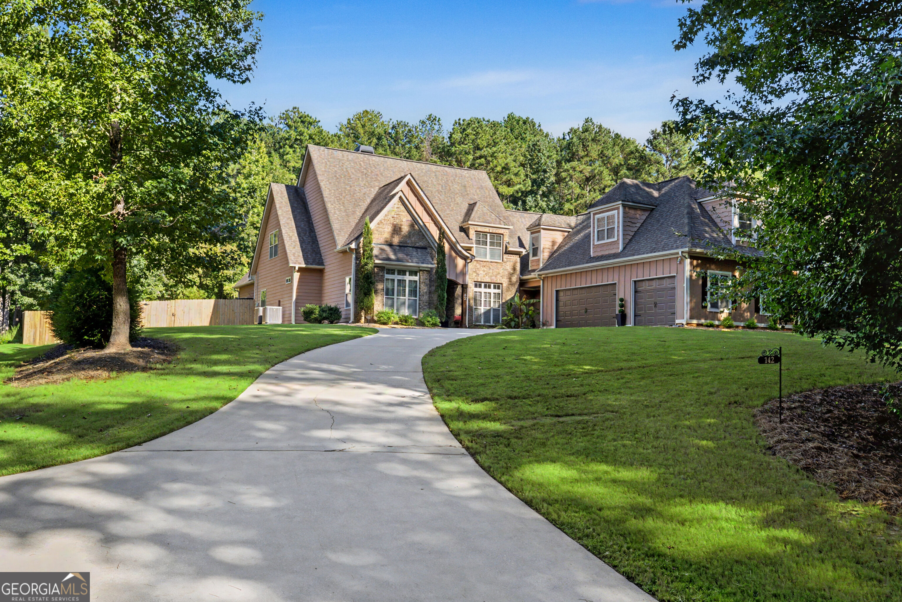 Large two-story home with stone accents, a curved driveway, and an attached two-car garage.