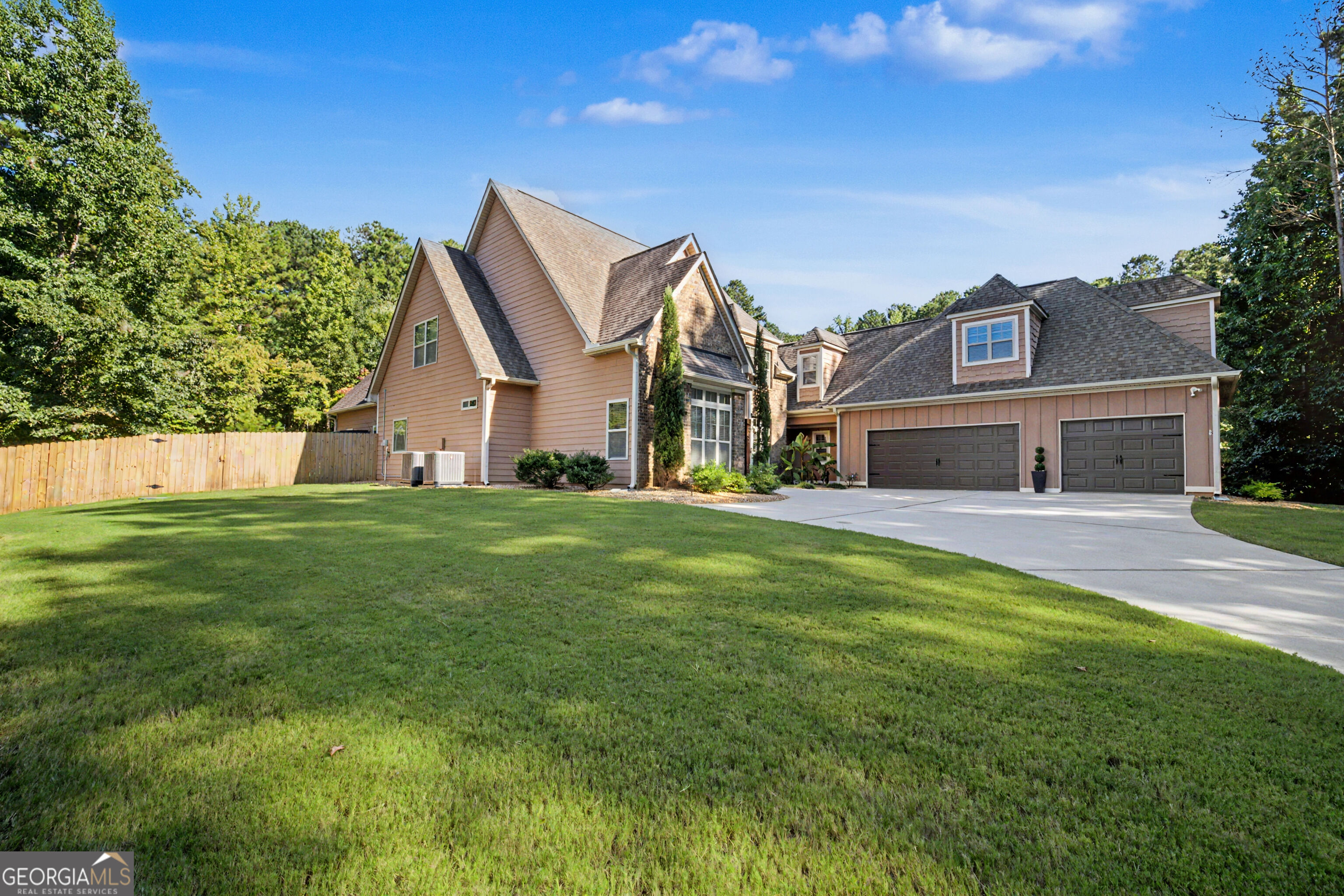 Large peach-colored home with multiple gables, stone accents, a two-car garage, and a broad driveway.
