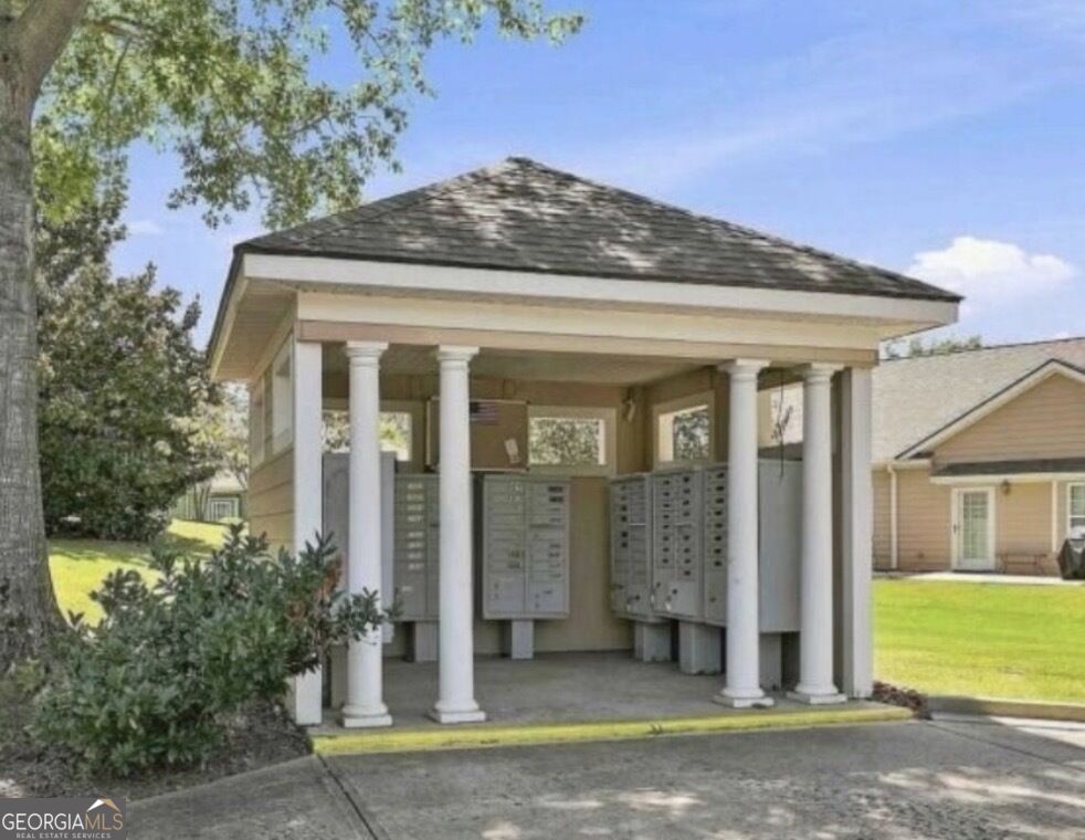 Covered community mailbox pavilion with white columns and rows of gray mailboxes.
