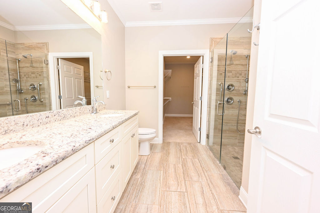 Bathroom with a long double vanity and glass-enclosed tiled shower.