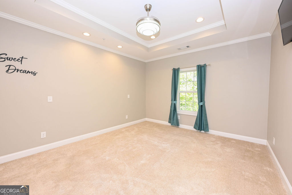 Empty bedroom with beige carpet, a tray ceiling, teal curtains, and a “Sweet Dreams” wall decal.