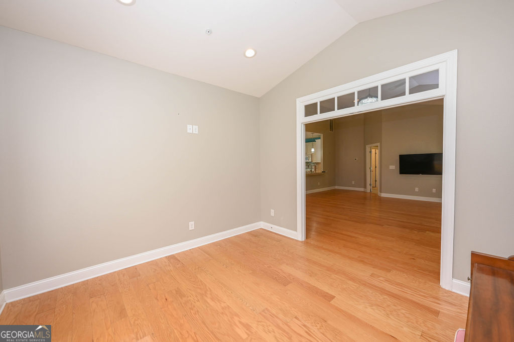 Unfurnished room with hardwood floors and a wide opening into the adjoining living area.
