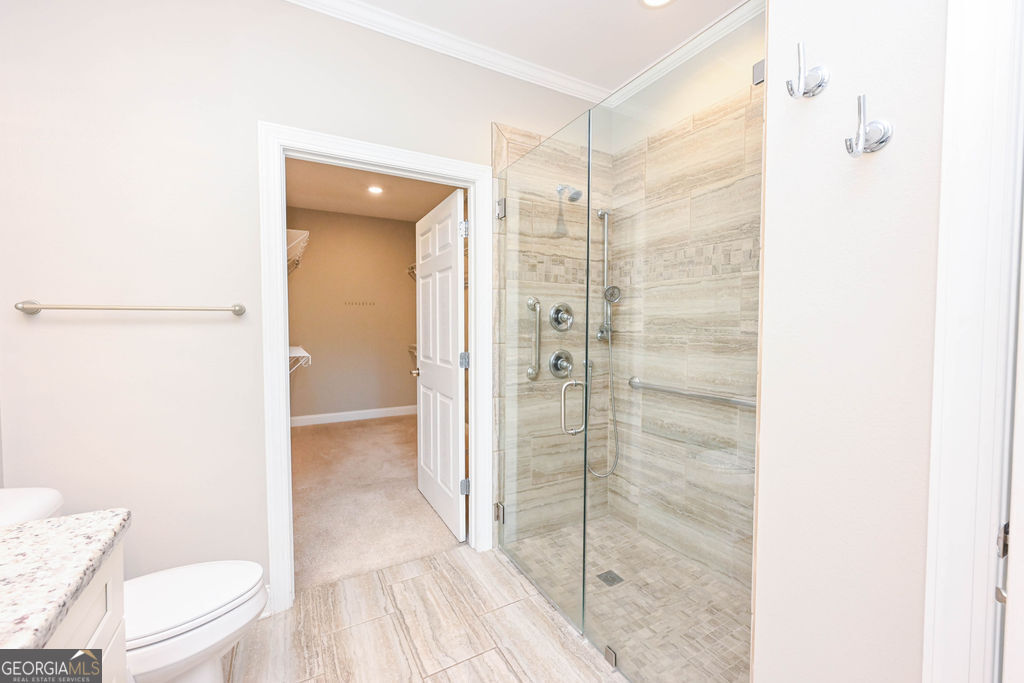 Bathroom with a frameless glass shower and beige stone-look tile.