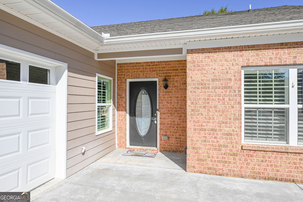 Home entrance with brick facade, oval-glass front door, and attached garage.
