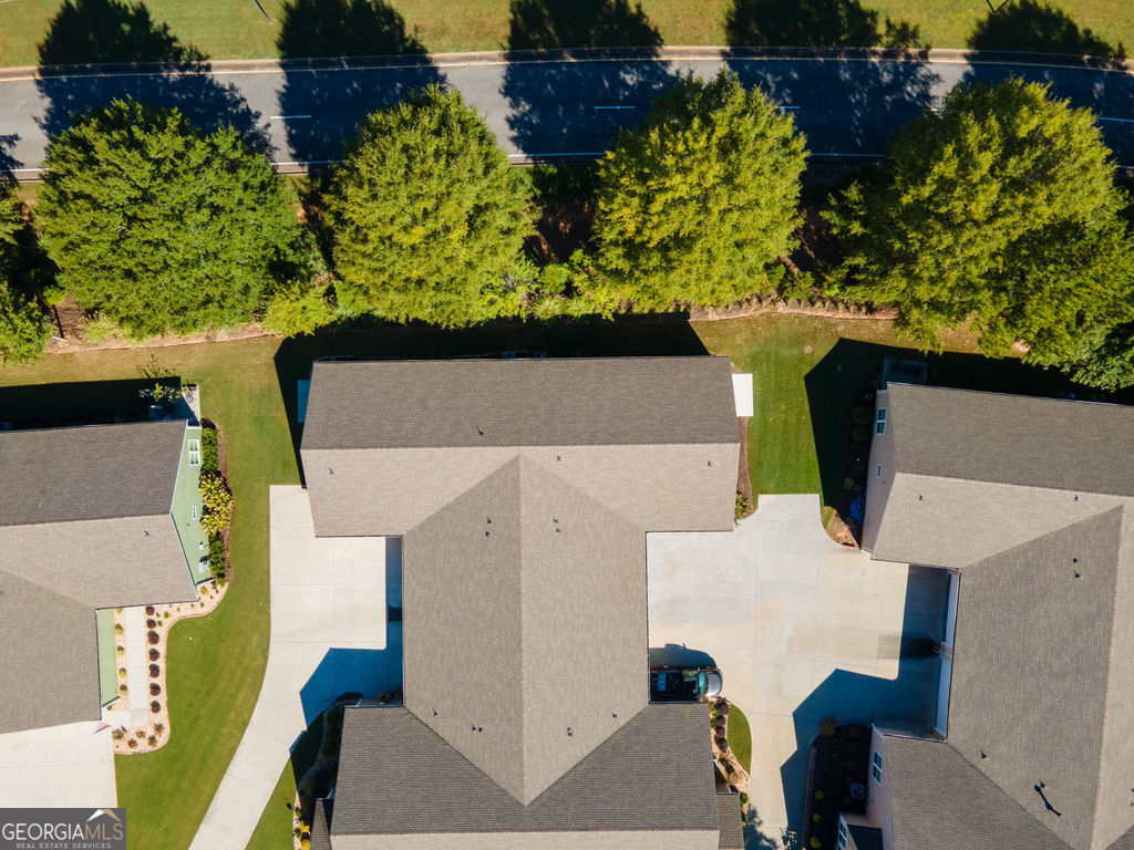 Aerial view of the home with its driveway, neighboring houses, and tree-lined road.