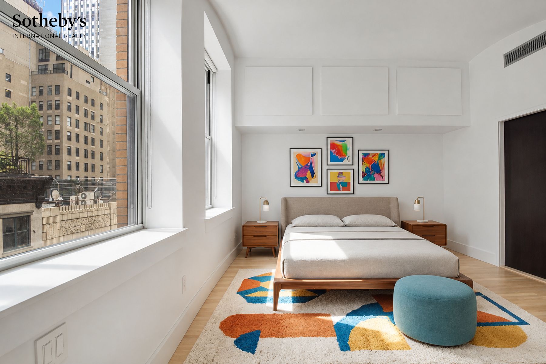 Bright bedroom with a large city-facing window, colorful artwork, and a neatly made bed.