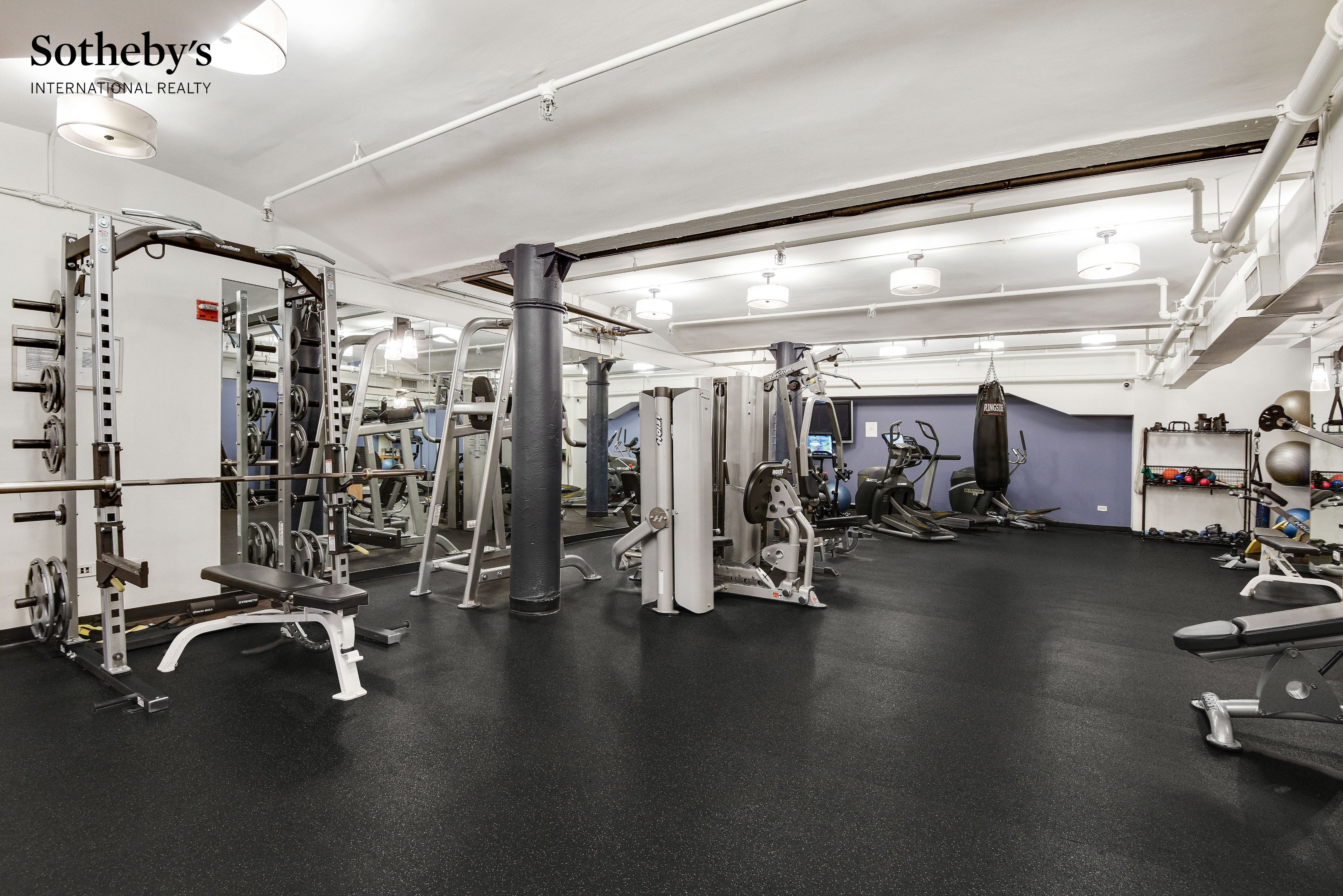 Building gym with weight machines, cardio equipment, and a hanging punching bag.