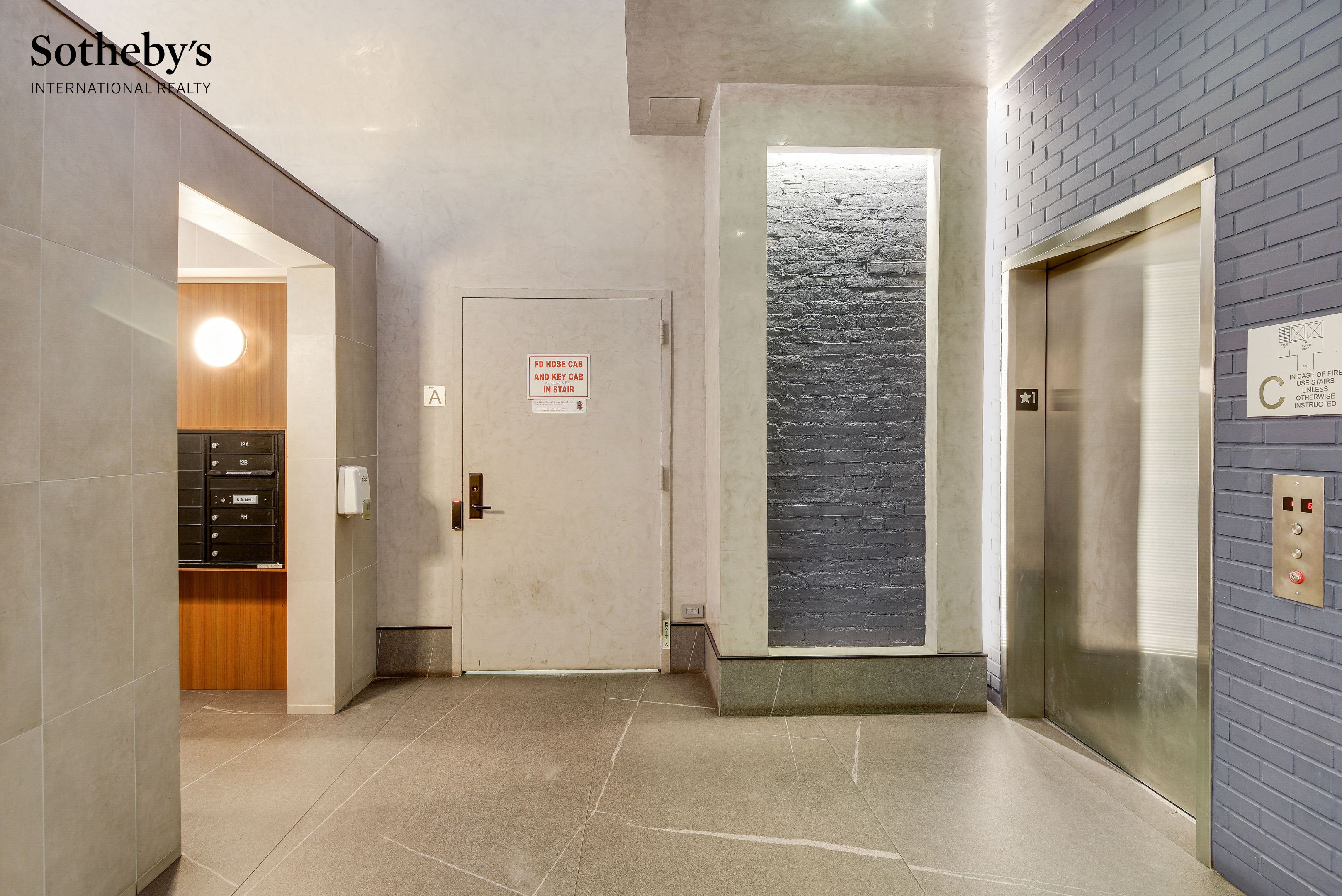Building lobby with stainless-steel elevator, tiled walls, and a recessed mailbox area.