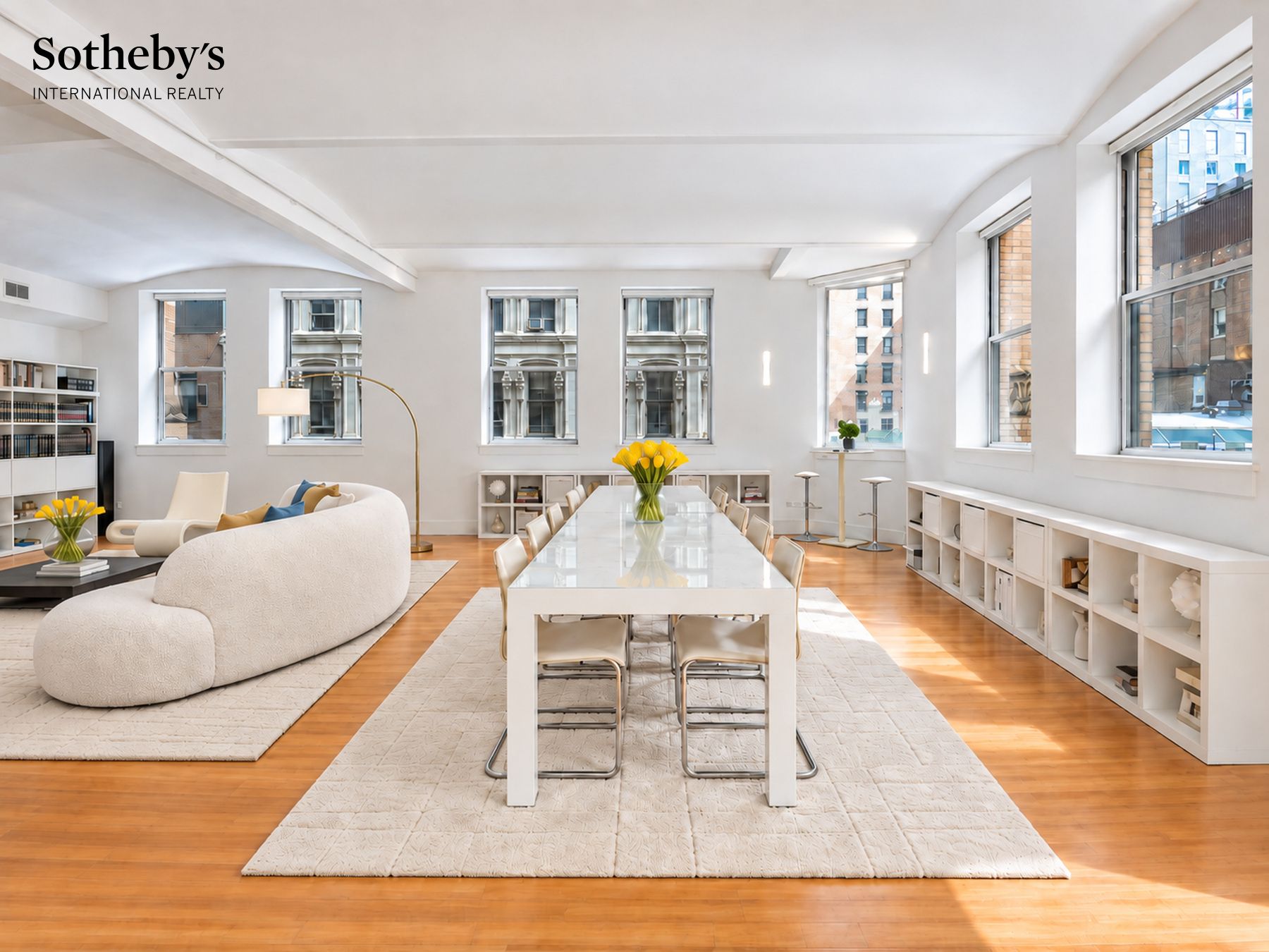 Staged open-plan living and dining room with expansive windows and a long white dining table.