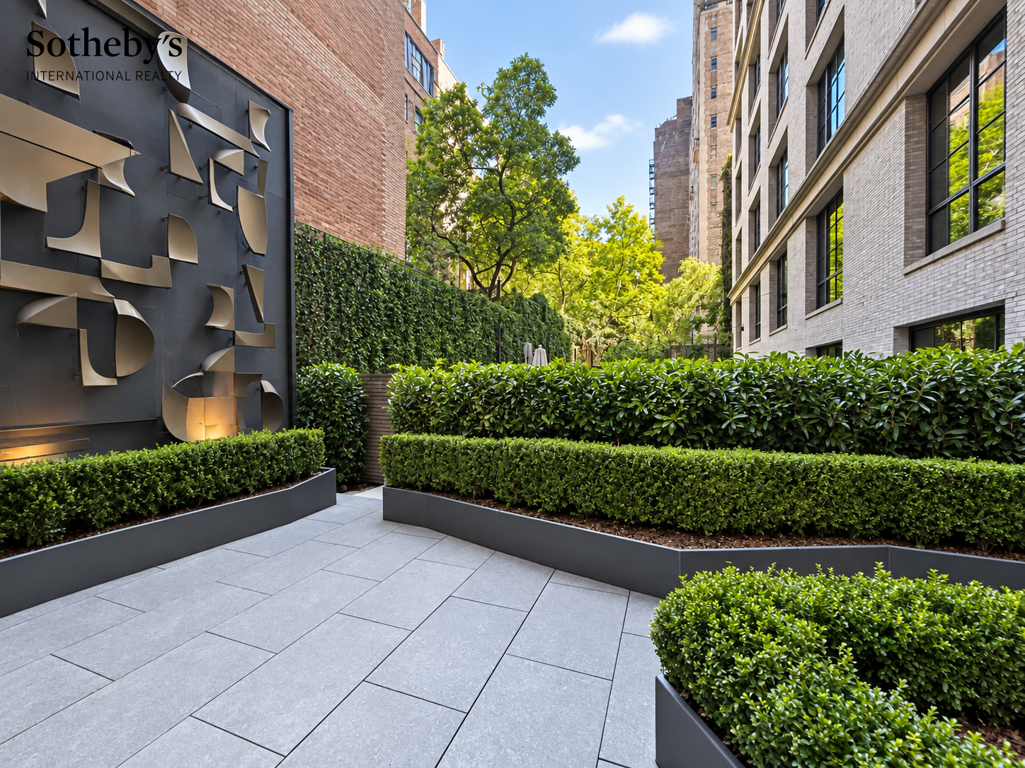 Landscaped courtyard with clipped hedges, mature trees, stone paving, and a sculptural metal wall.