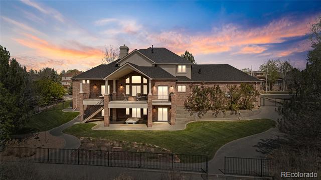 Two-story brick house with broad windows and landscaped grounds beneath a pink and blue sunset.