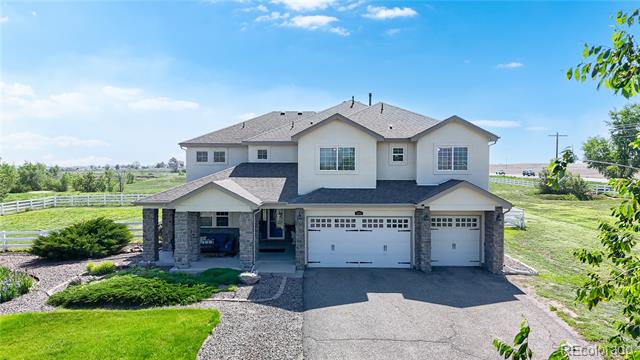 Two-story house with stone accents, a covered porch, and a three-car garage beside open fields.