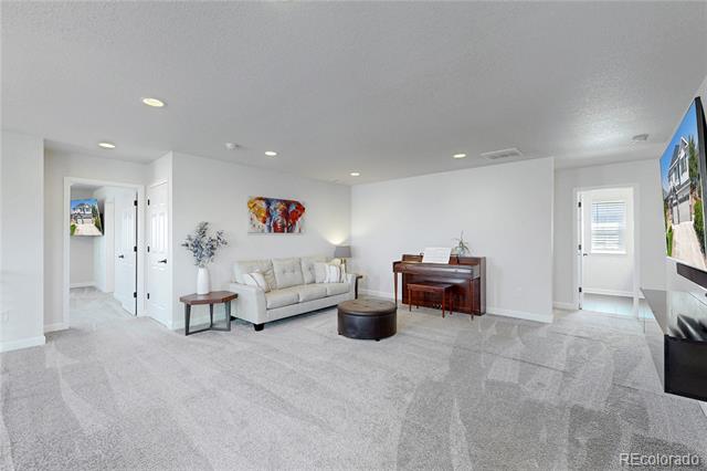Living room with a cream sofa, dark piano, and light gray carpet.