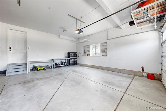 Spacious garage with a concrete floor, workbench, and tool cabinets.