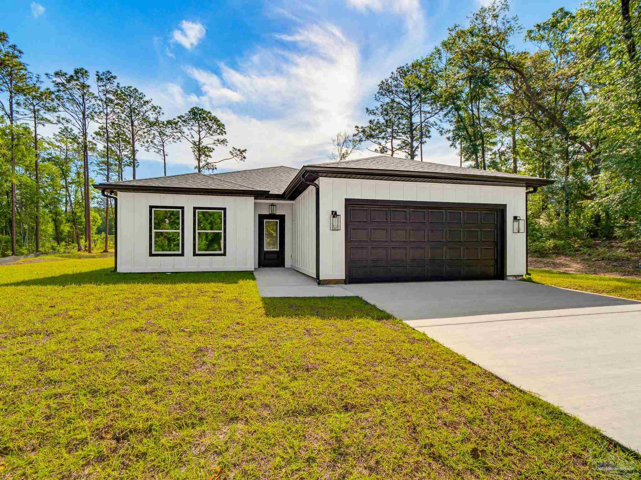 Modern white single-story home with black trim, a dark double garage door, and a concrete driveway.