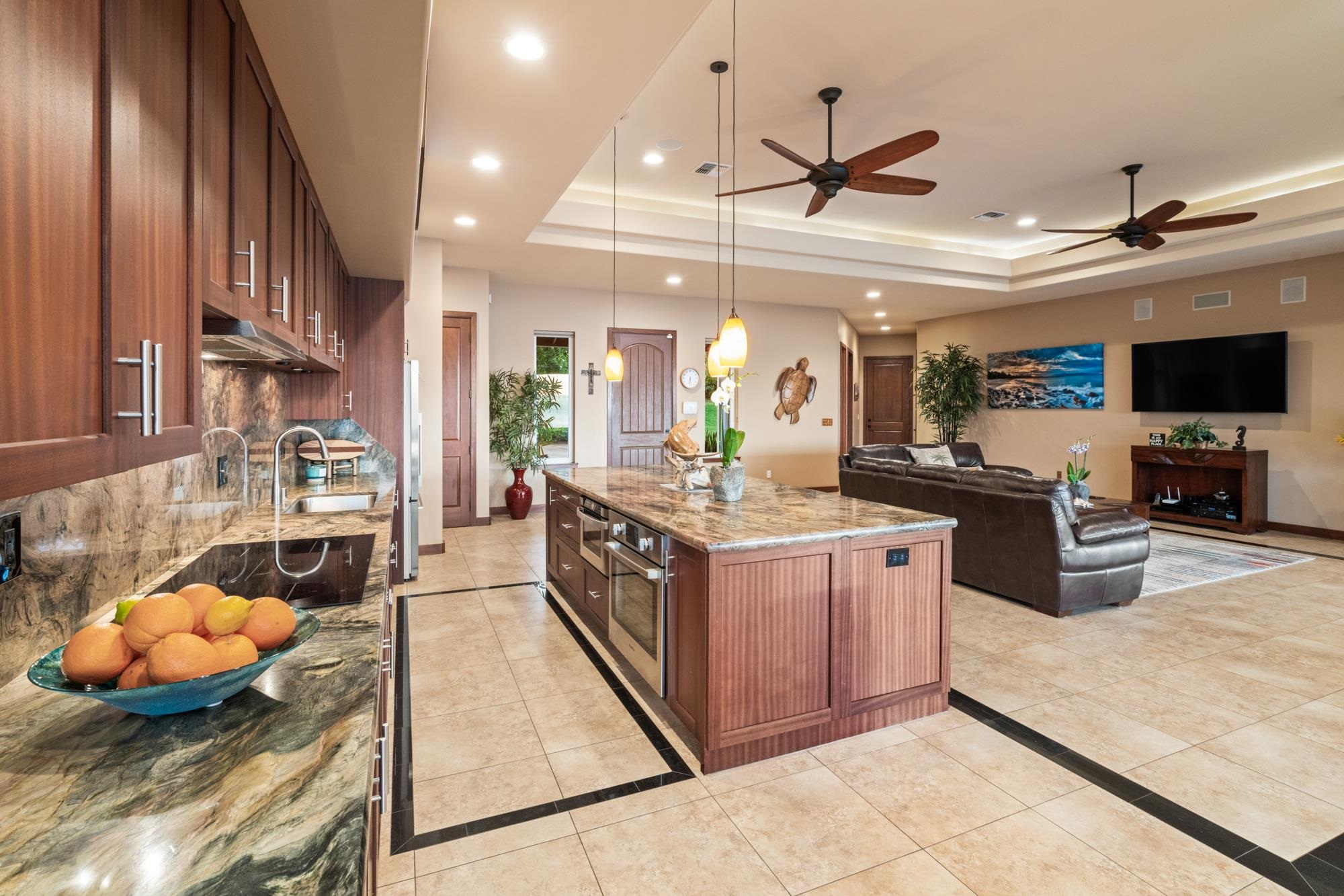 Open-plan kitchen and living room with a large stone island and dark wood cabinetry.