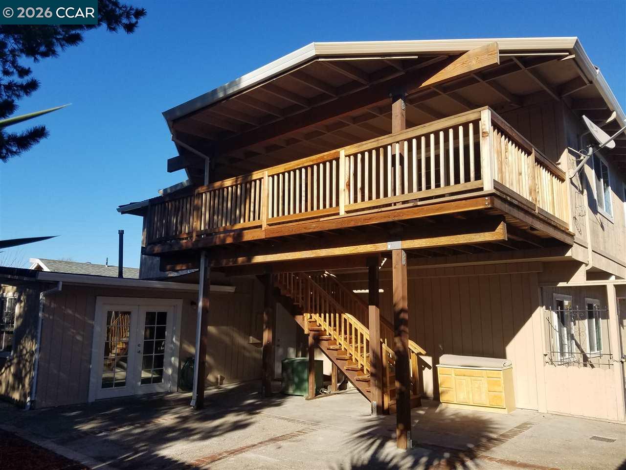 Home exterior with a large elevated wooden deck, covered patio, and outdoor staircase.