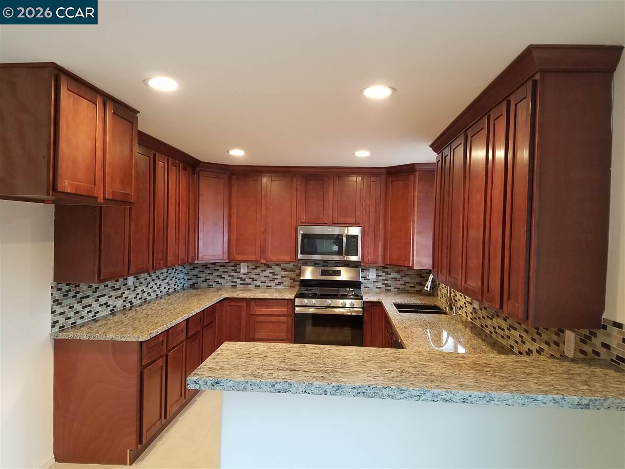 Kitchen with extensive wood cabinetry, granite counters, mosaic backsplash, and stainless steel appliances.