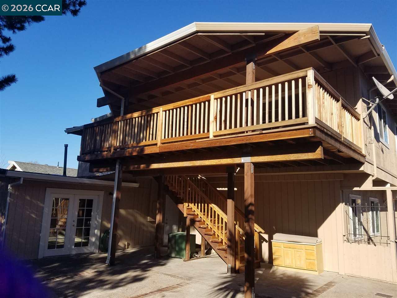 Rear of a two-story home with a large covered wooden deck and exterior staircase.