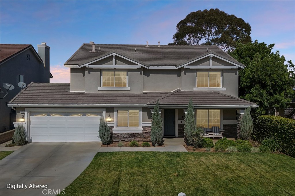 Two-story gray house with a white double garage, stone accents, and landscaped front lawn.