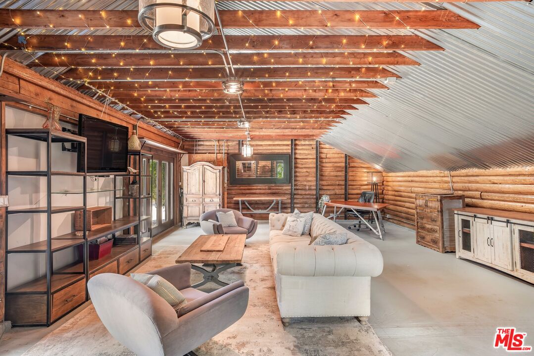 Rustic loft living room with exposed timber beams, string lights, and a white sofa.