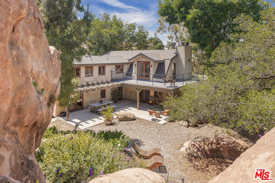 West Hills home with a raised deck and covered patio, framed by large natural rock formations.