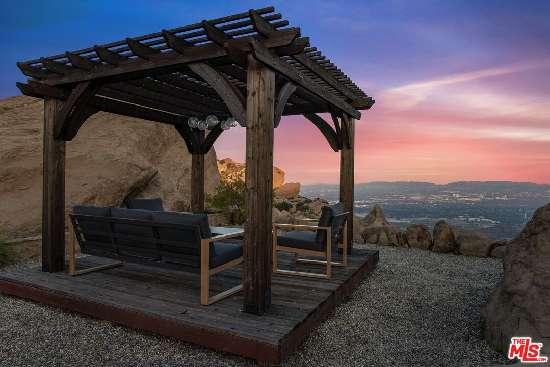 Pergola seating area overlooking the city and hills at dusk.