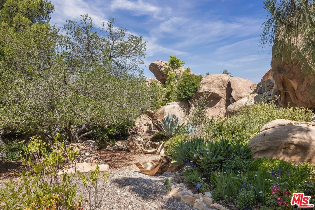 Rock garden with a gravel path, succulents, and a wooden lounge chair.