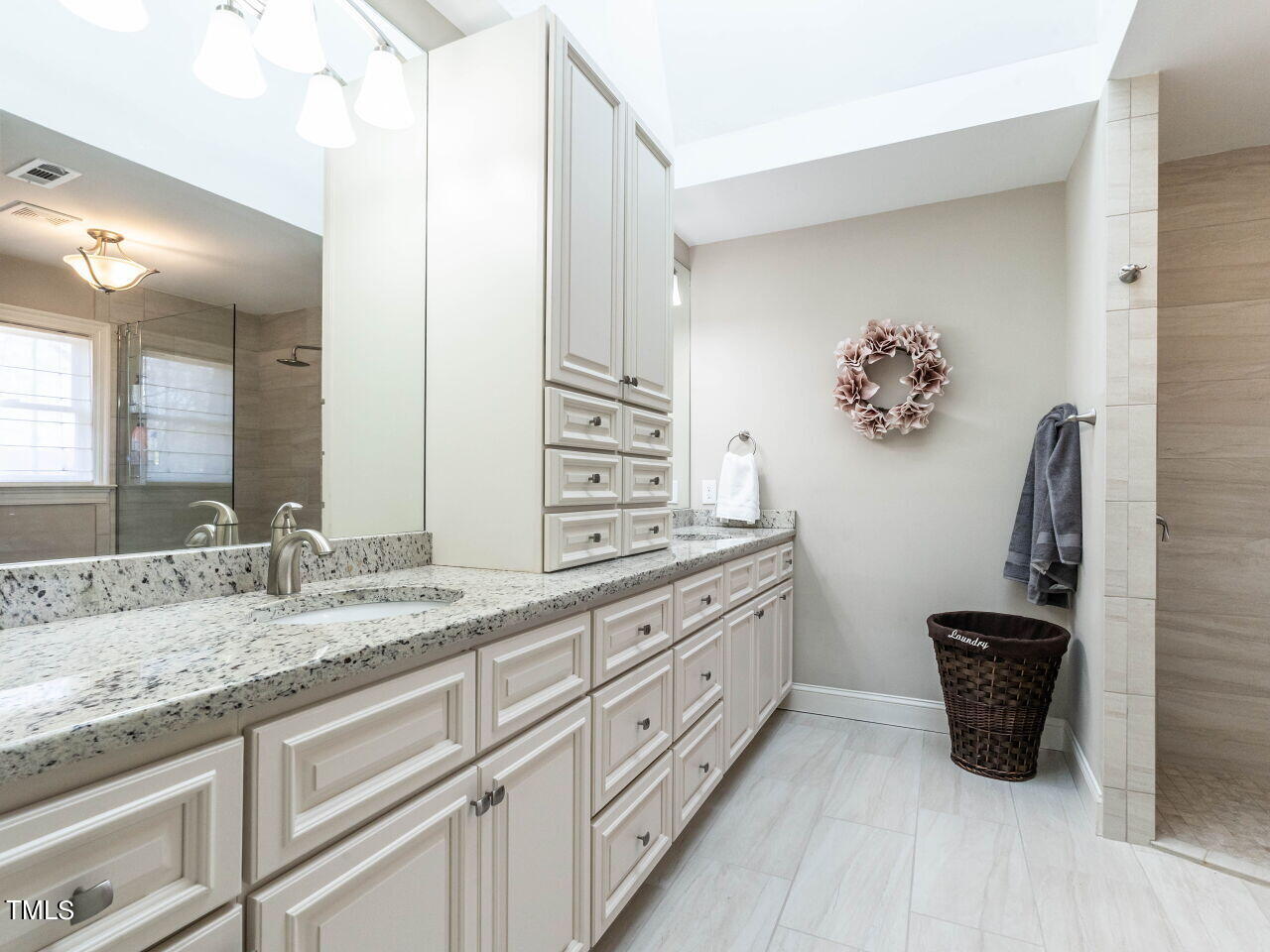 Bathroom with a long granite-topped vanity and a glass-enclosed walk-in shower.