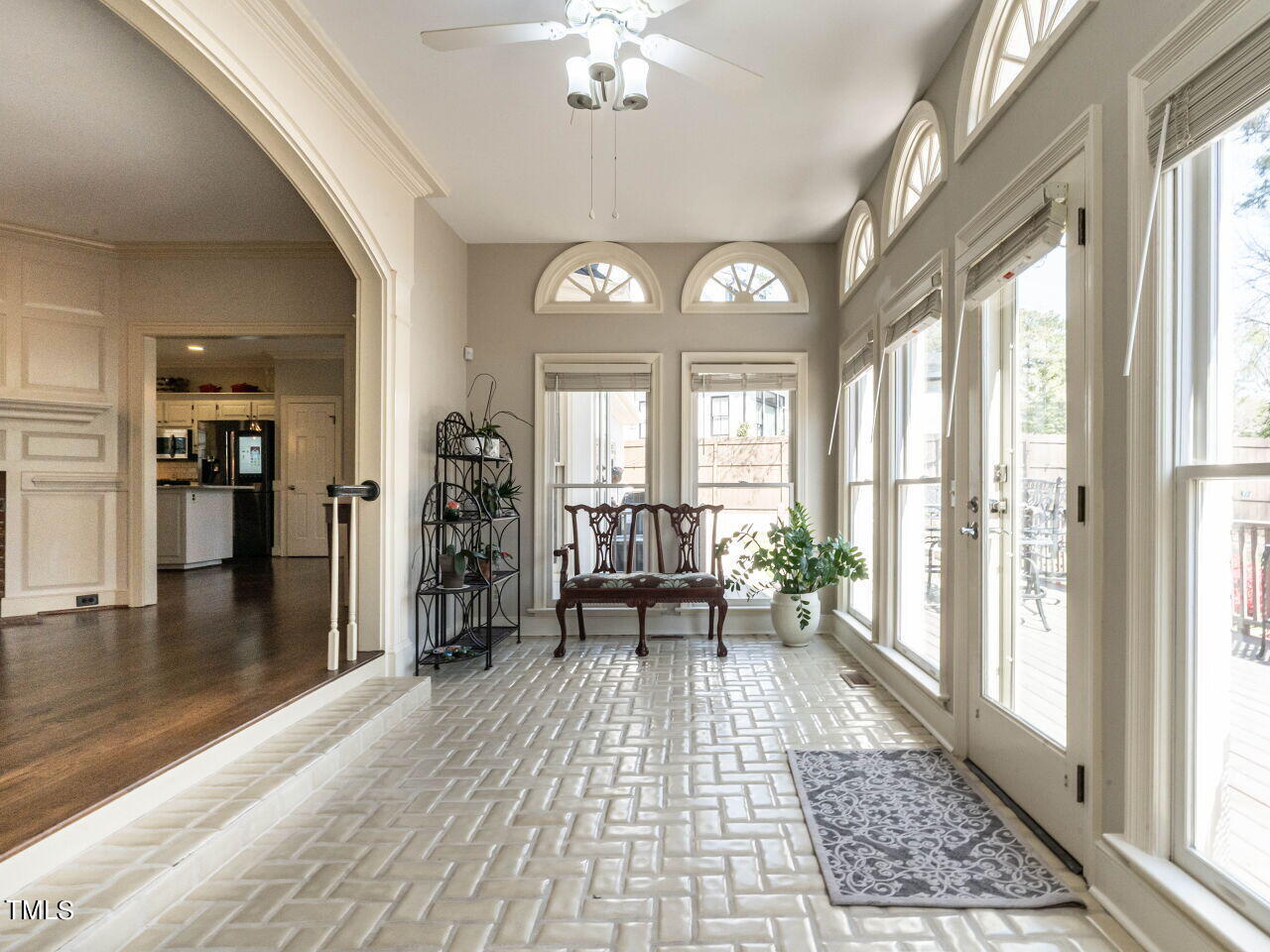 Furnished sunroom with a tiled floor, tall windows, and arched transoms.