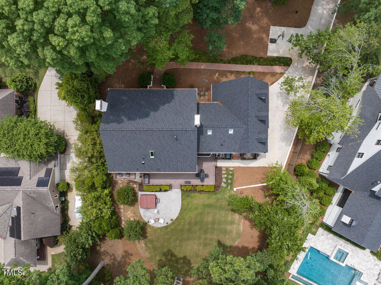 Aerial view of a Cary home with a broad roof, leafy yard, patio, and lawn.