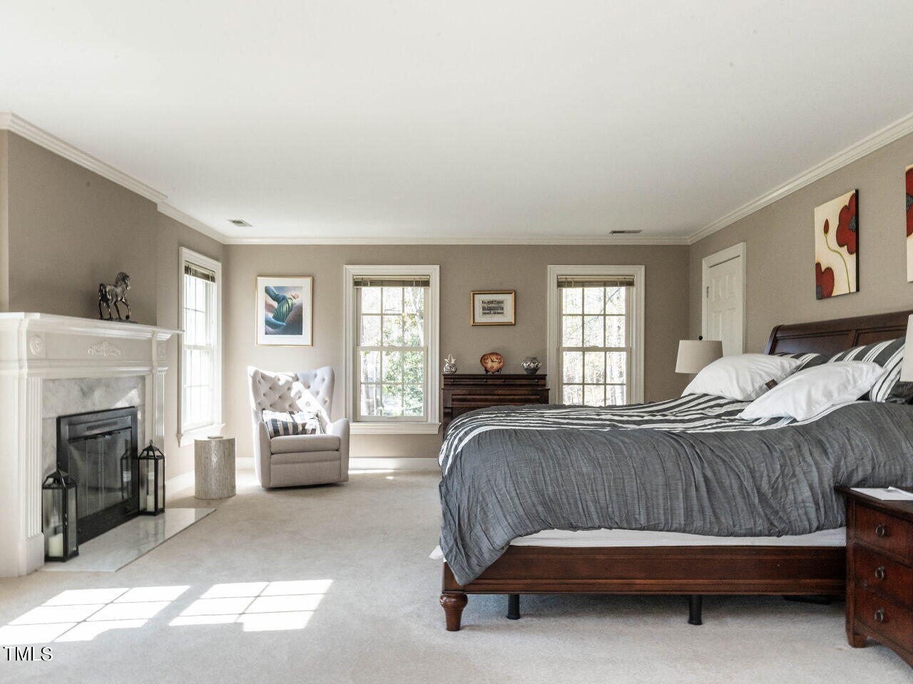 Bedroom with a dark wood bed, gray striped bedding, and a white fireplace.