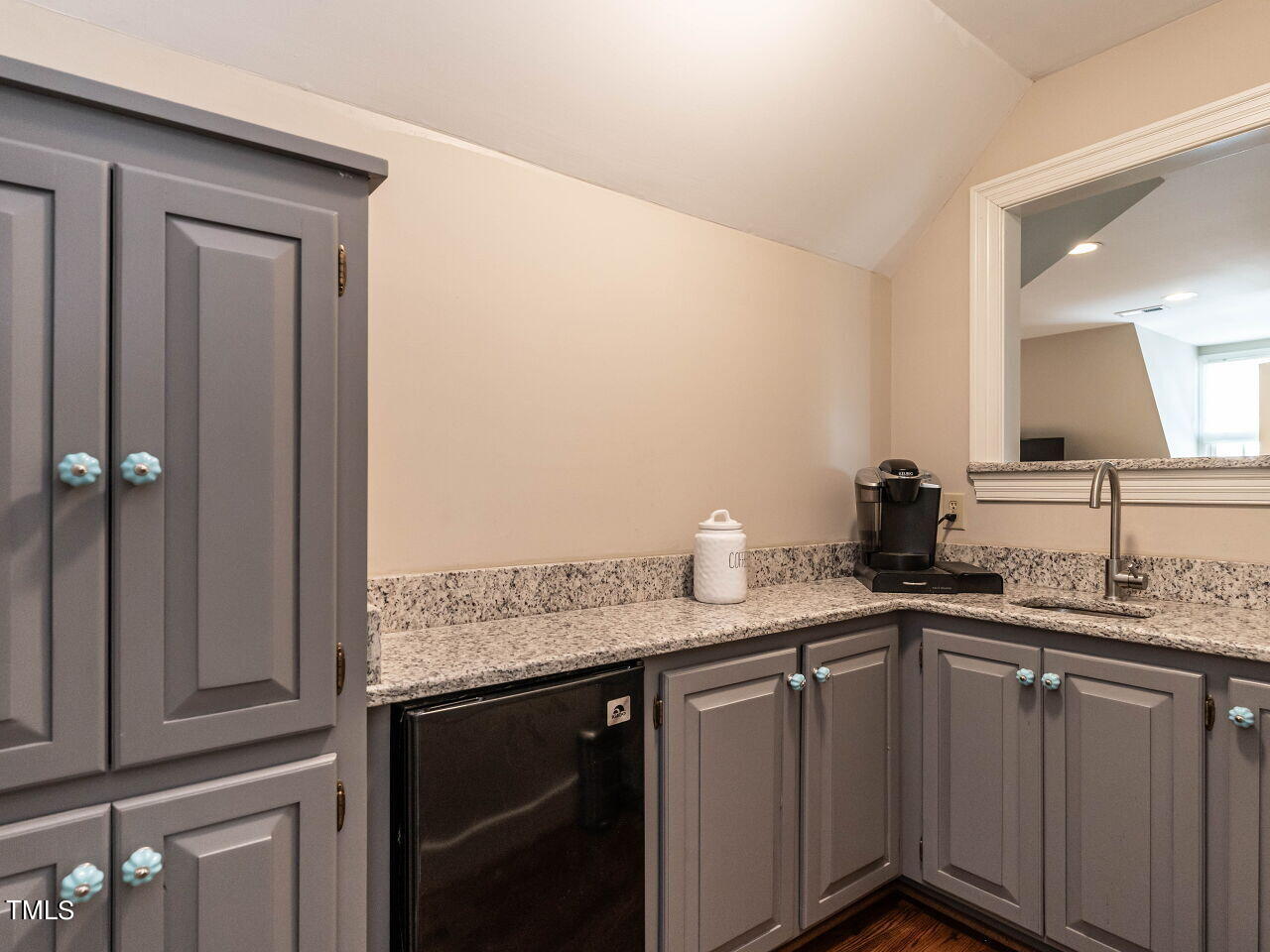 Wet bar with gray cabinets, granite counters, a small sink, and an under-counter beverage refrigerator.