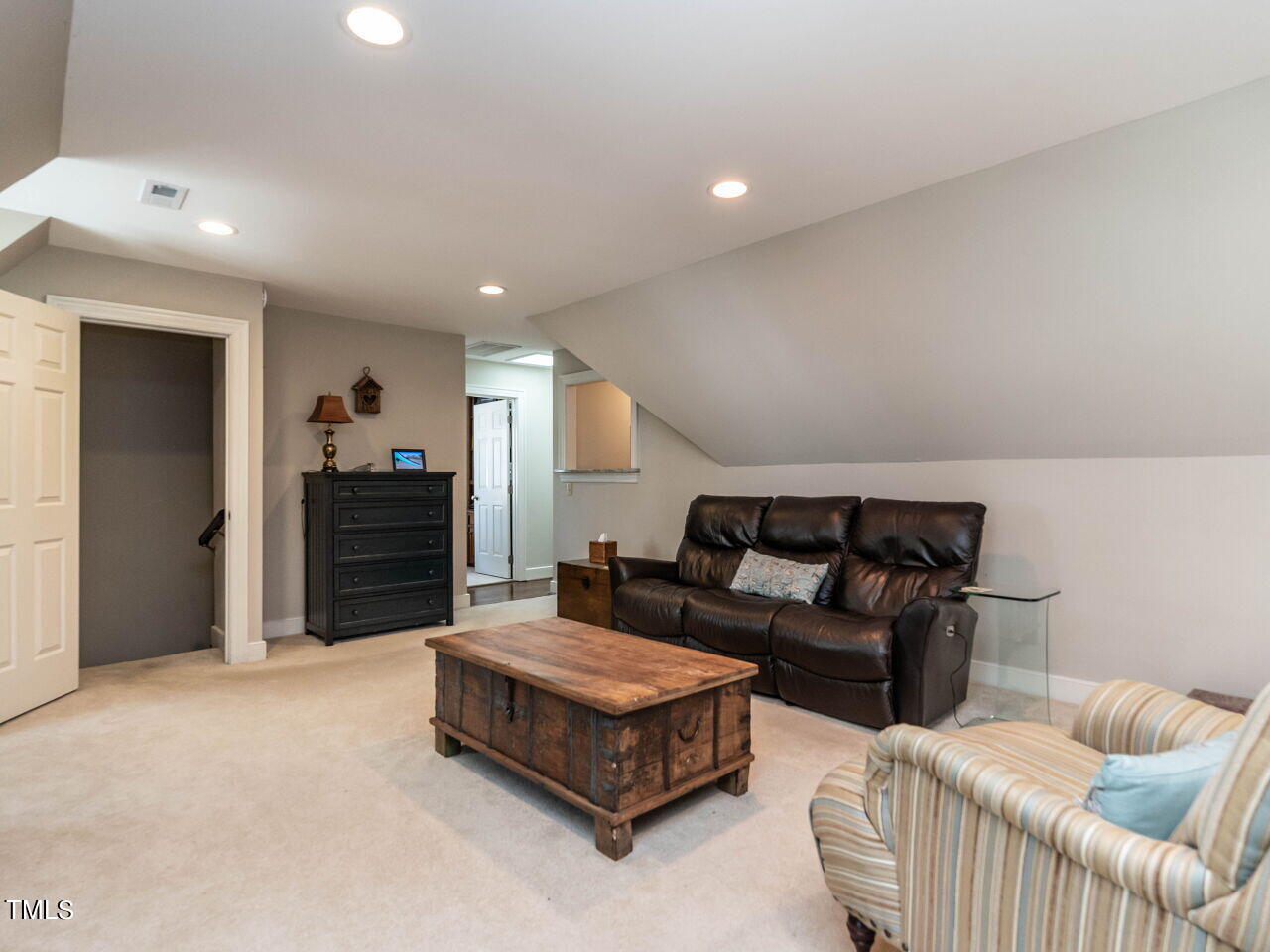 Living room with a sloped ceiling, leather sofa, and rustic wooden coffee table.