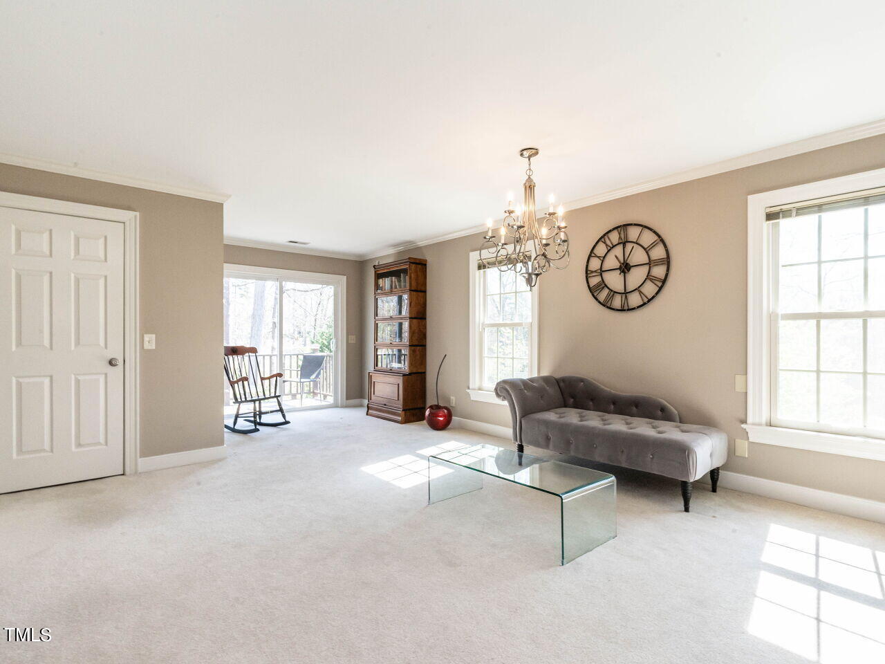 Living room with a gray chaise, glass coffee table, chandelier, and deck access.