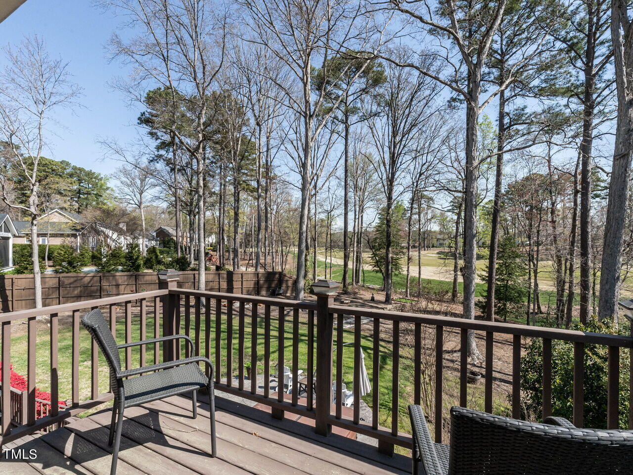 Deck with outdoor chairs overlooking a wooded backyard and golf course.