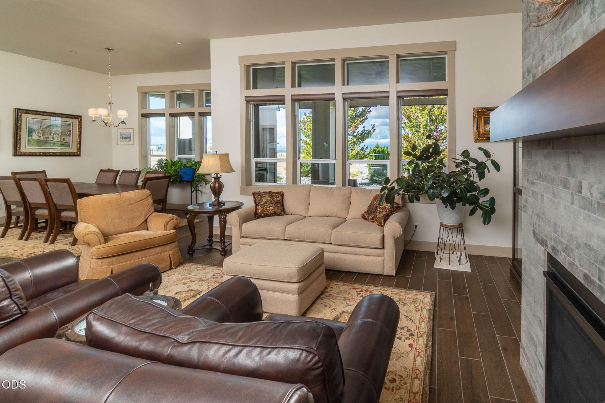 Living room with large windows, beige seating, and a gray stone fireplace.
