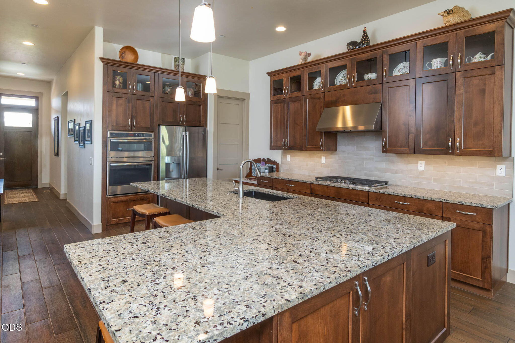 Kitchen with dark wood cabinets, stainless steel appliances, and a large granite island.