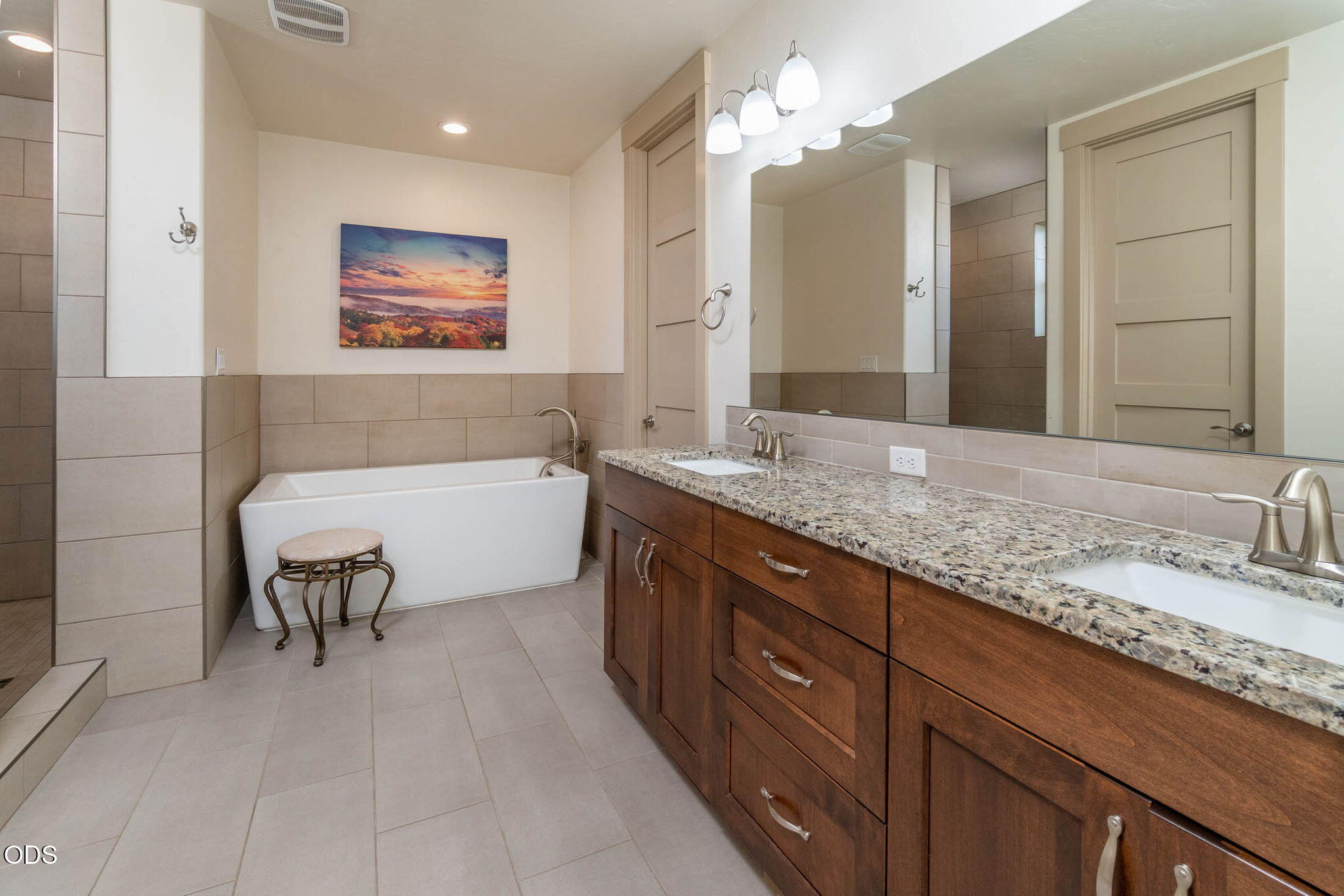 Bathroom with a soaking tub and double-sink vanity topped with speckled stone.