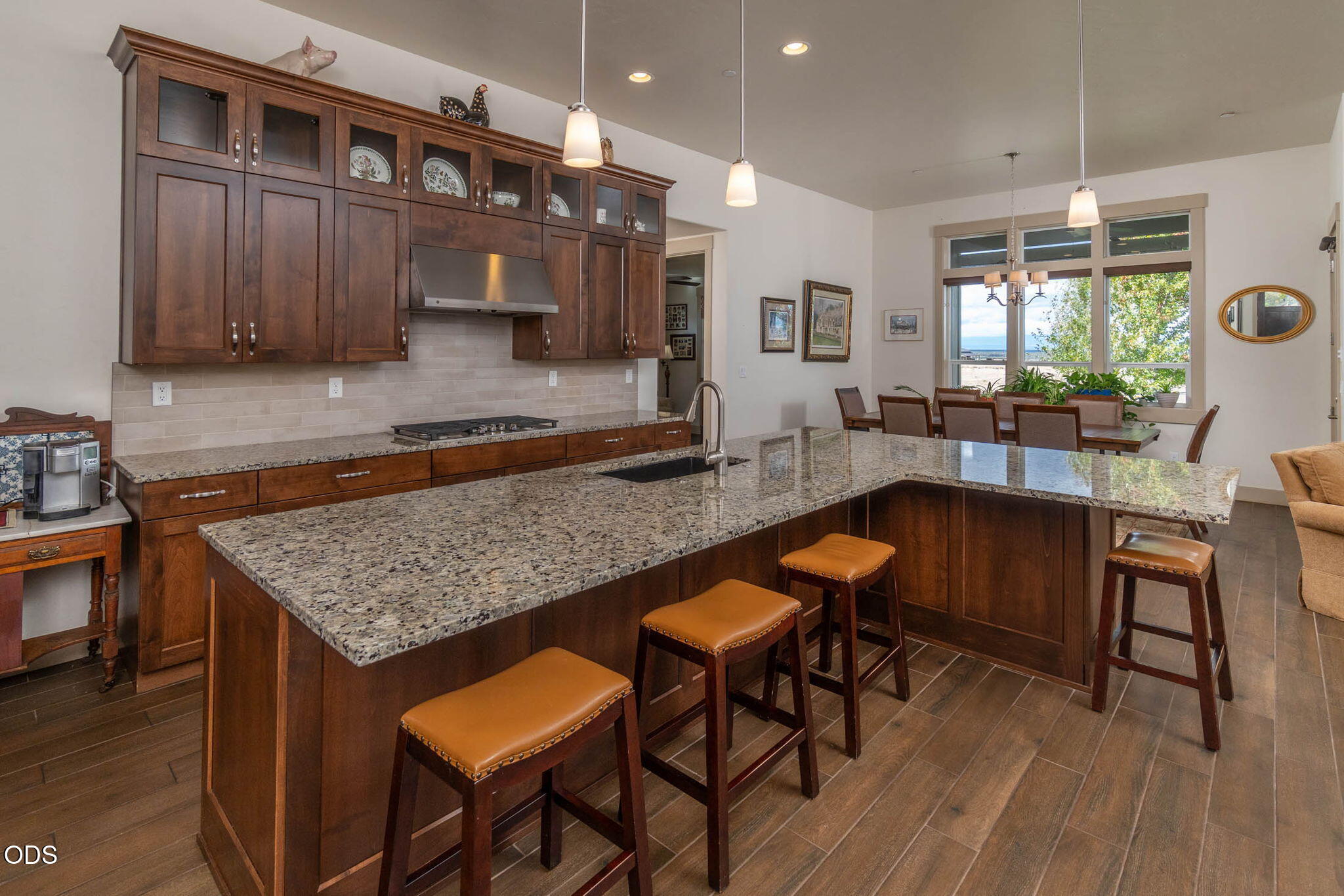Kitchen with a large granite island, dark wood cabinetry, and adjoining dining area.