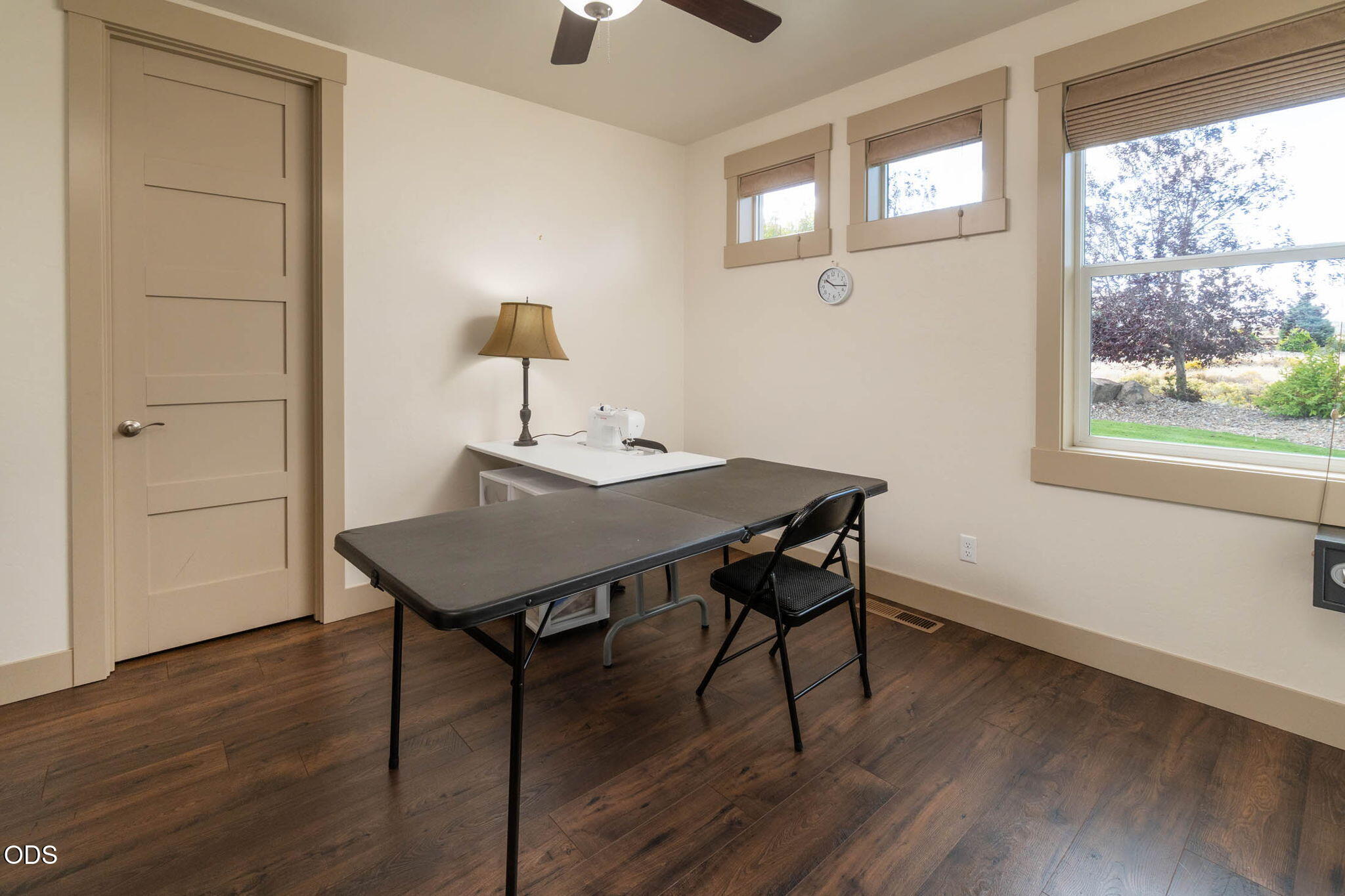 Sewing room with a machine, folding worktable, and large windows overlooking the yard.