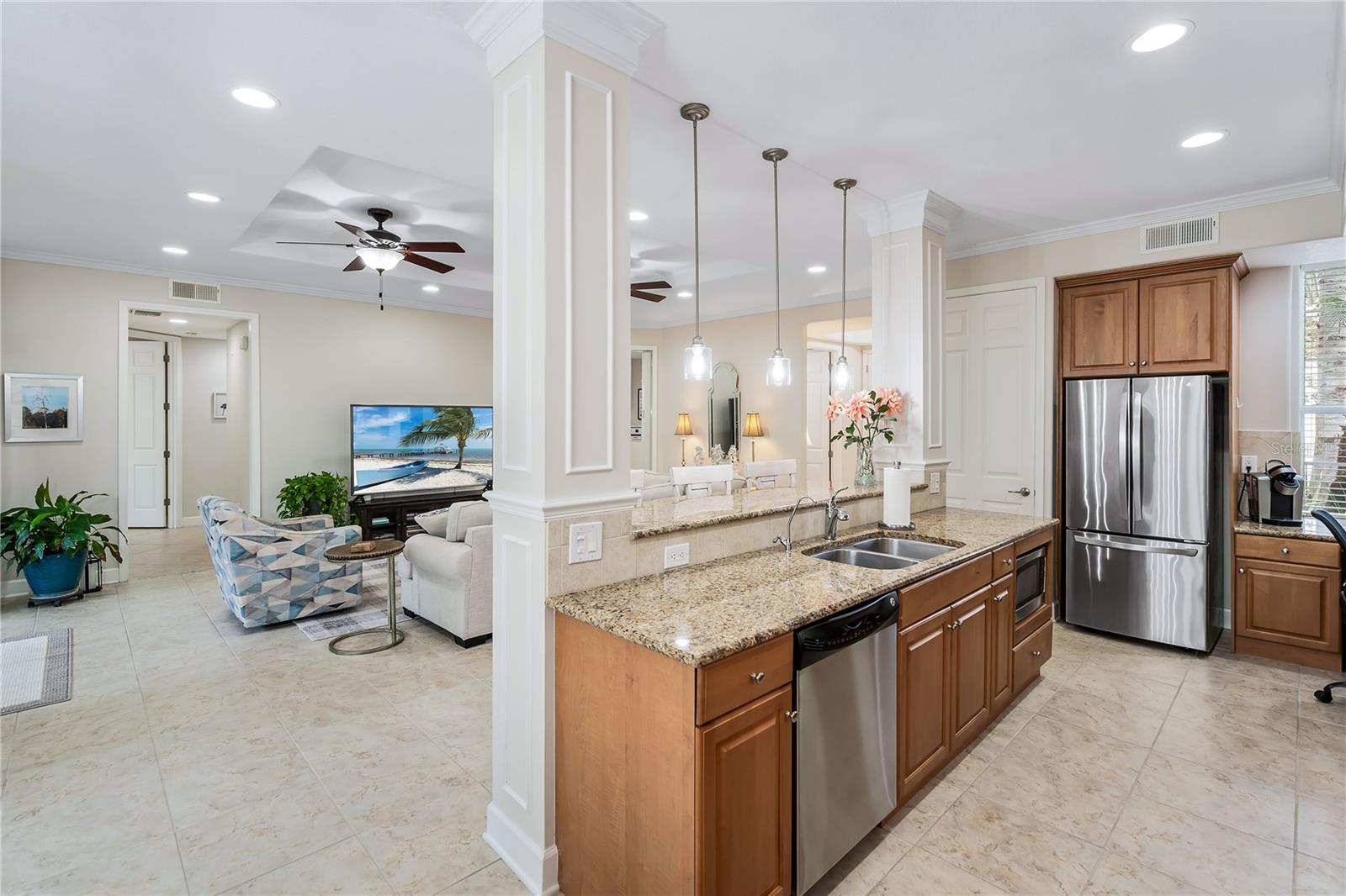 Open-plan kitchen with a granite island and stainless appliances beside a furnished living area.